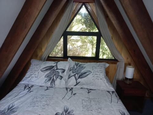 Bett in einem Zimmer mit Fenster in der Unterkunft Donde Coco in Quellón