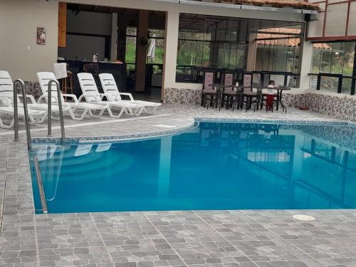 a large swimming pool with chairs and a table at Veronica lookout Hotel in Urubamba