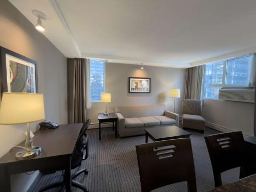 カルガリーにあるCoast Calgary Downtown Hotel & Suites by APAのソファとリビングルームが備わるホテルルームです。