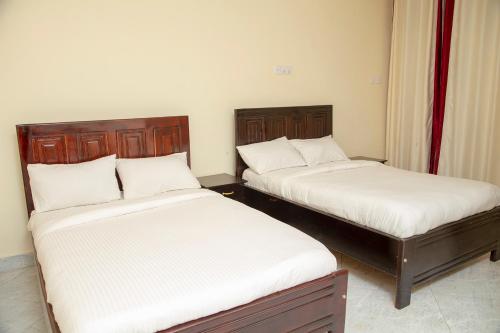 2 Betten in einem kleinen Zimmer mit Röcken in der Unterkunft Eziana palm Hotels 