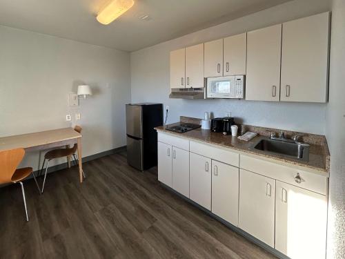a kitchen with white cabinets and a sink and a desk at Studio 6 Lubbock, TX in Lubbock