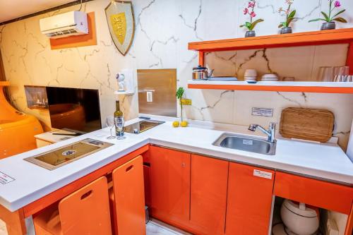 Hongcheon Botopia Healing Park في هونغتشان: مطبخ صغير مع خزائن برتقال ومغسلة
