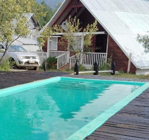 a blue swimming pool in front of a house at Cabana Vista Nevada in Nevados de Chillan