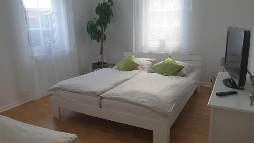 a white bed with green pillows in a room at Moderner Fachwerktraum in Uetze