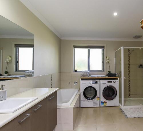 a bathroom with a washing machine and a bath tub at Riverside Haven in Healesville