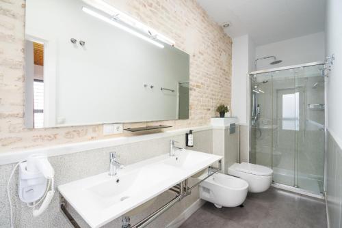 ein Badezimmer mit einem Waschbecken, einem WC und einem Spiegel in der Unterkunft Plaza de Armas in Sevilla