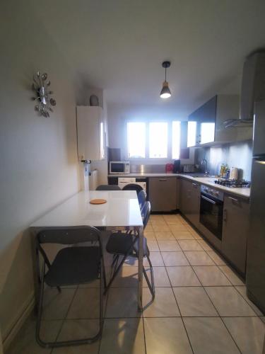 une cuisine avec une table blanche et des chaises dans l'établissement T3 cosy, calme & lumineux proche Eurexpo, Groupama, à Saint-Priest