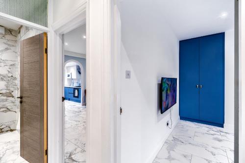 a hallway with blue doors and marble flooring at Luxurious 2 bedroom flat with parking and garden, 5 mins walk to train station and bus stop opposite property in London