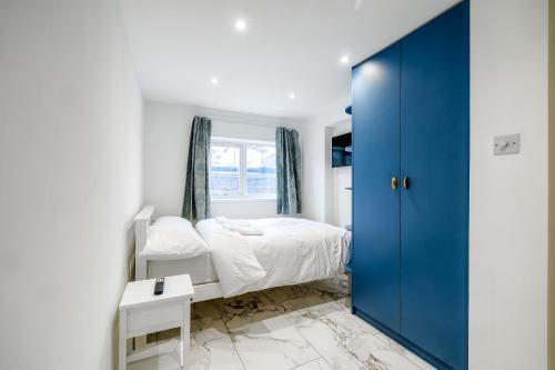 een slaapkamer met een bed en een blauwe deur bij Luxurious 2 bedroom flat with parking and garden, 5 mins walk to train station and bus stop opposite property in Londen