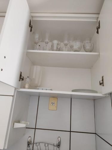 a kitchen with white cabinets and shelves with dishes at Loft completo na Asa Sul próximo da P Federal ENAP LBV Aeroporto CASV , Rodov Interestadual e parque da cidade in Brasília