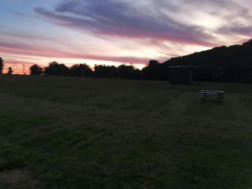 eine Bank, die bei Sonnenuntergang auf einem Feld sitzt in der Unterkunft Eden in Queilén