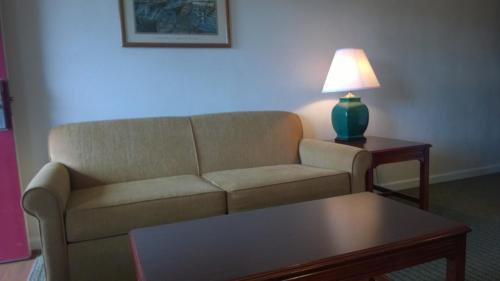 a living room with a couch and a table with a lamp at Affordable Suites Charlottesville in Charlottesville