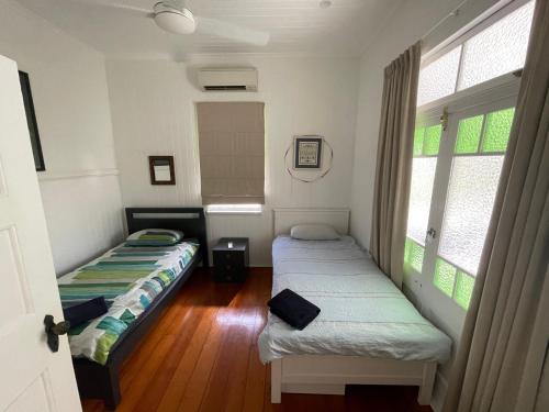 two beds in a room with two windows at Neat, Tidy and Central in Brisbane