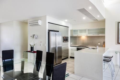 a kitchen with a refrigerator and a table and chairs at Monaco Caloundra in Caloundra