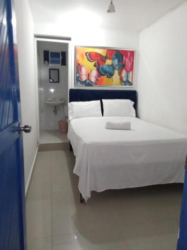 Un dormitorio con una cama blanca y una pintura en la pared en HOSTAL BARRANQUILLA INN en Barranquilla