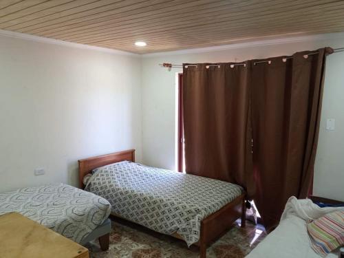 1 dormitorio con 2 camas y una ventana con cortinas en Casa de campo, en Pichilemu