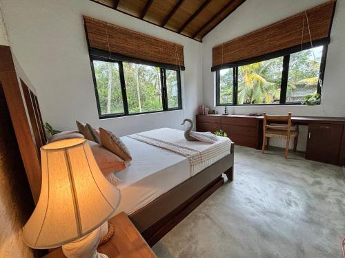 a bedroom with a bed with a lamp and two windows at Rai Villa Colombo in Colombo