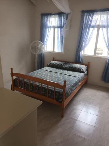 a bedroom with a bed with blue curtains and a fan at Super breezy cozynook ! in Bridgetown