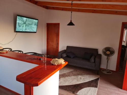 a living room with a couch and a tv on the wall at Cabaña Full Equipada in El Quisco