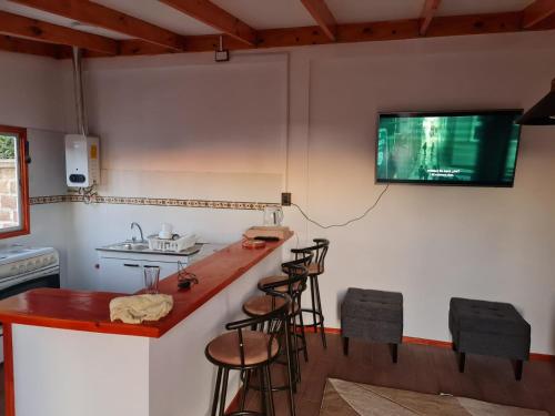 una cucina con bar con sgabelli e una TV a parete di Cabaña Full Equipada a El Quisco