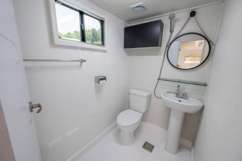 uma casa de banho com um WC, um lavatório e um espelho. em Gapyeong Olden Caravan & Pension - Pet Friendly em Gapyeong