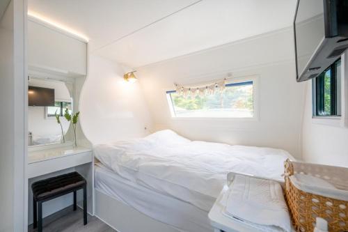 a white bedroom with a bed and a mirror at Gapyeong Olden Caravan & Pension - Pet Friendly in Gapyeong
