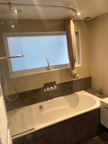 uma banheira na casa de banho com uma janela em Chart Cottage em Stanmore
