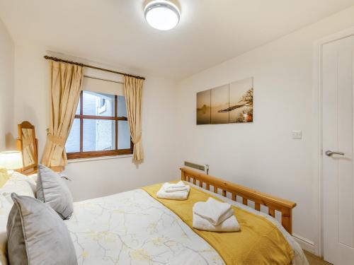 a bedroom with a bed with yellow sheets and a window at Kissing Gate in Keswick