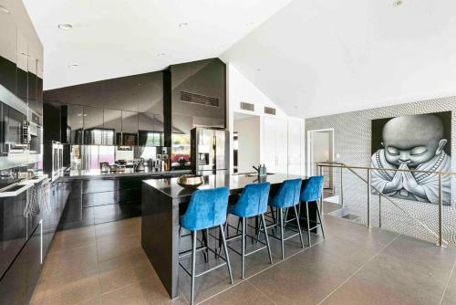 a kitchen with a bar with blue bar stools at Modern spacious 3 bedroom penthouse in Enmore in Sydney