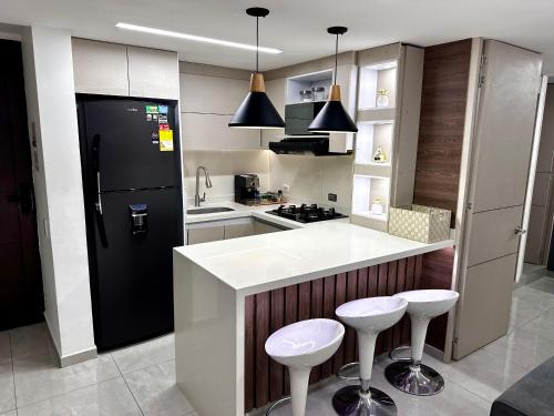 - une cuisine avec un réfrigérateur noir et deux tabourets dans l'établissement Apartamento luxury Girardot, à Girardot