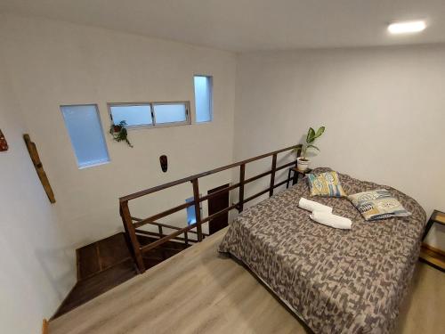 a bedroom with a bed and a staircase with windows at Urutau Loft in Puerto Iguazú