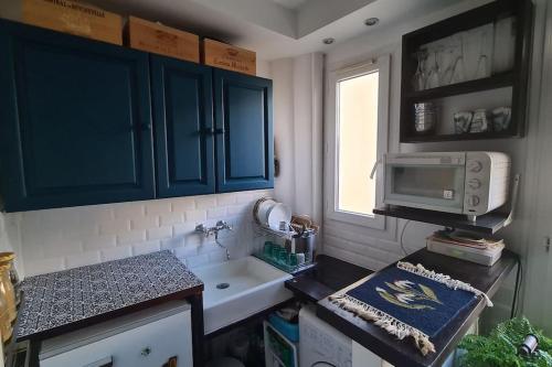 une cuisine avec un évier et un micro-ondes dans l'établissement Logement entier - 2B/R 3 min de Butte aux cailles, à Paris