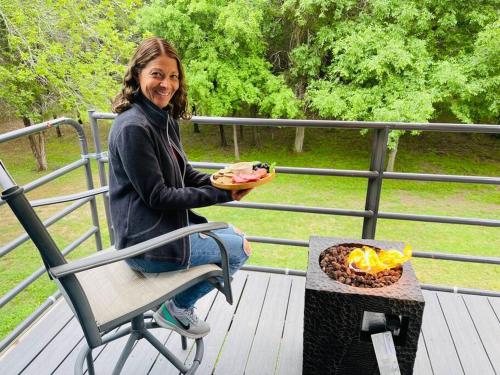 a woman sitting in a chair holding a plate of food at Bastrop Tiny Disc Golf Retreat in Bastrop
