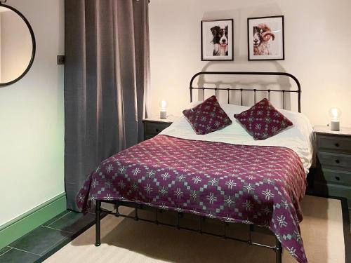 ベトウス・ア・コーエドにあるCoed Mawrのベッド1台(紫の毛布、枕2つ付)