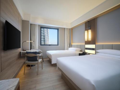 a hotel room with two beds and a desk at Courtyard By Marriott Shanghai Xujiahui in Shanghai