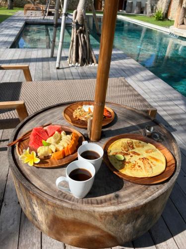 dos platos de comida en una mesa junto a una piscina en Acacia Bungalows Bingin, en Uluwatu