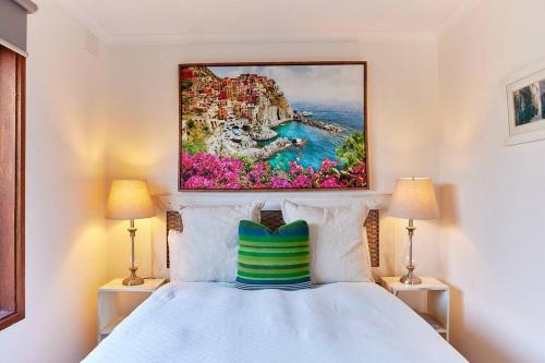 ein Schlafzimmer mit einem Bett und einem Gemälde an der Wand in der Unterkunft Rose Cottage - Right in town in Healesville