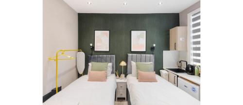 two beds in a room with green walls at Happy Haven: Fun Studio Perfect for Travelers in London