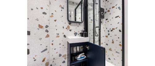 a bathroom with a sink and a rock wall at Happy Haven: Fun Studio Perfect for Travelers in London