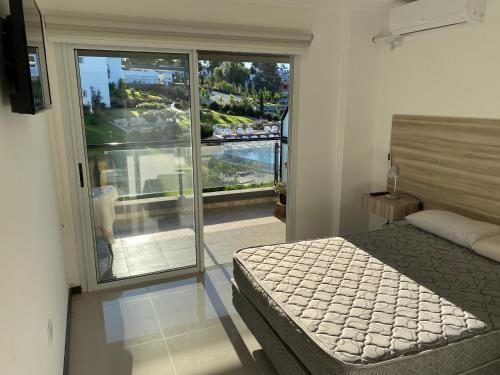 1 dormitorio con 1 cama y balcón con vistas. en Veneto Departamento Complejo Vacacional y Spa PB en Villa Santa Cruz del Lago