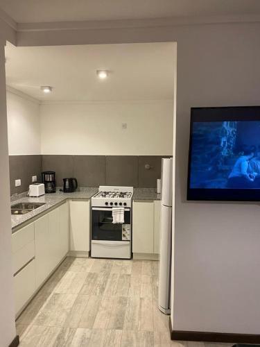 a kitchen with a stove and a tv on a wall at Duplex del Parque y Balneario in Necochea