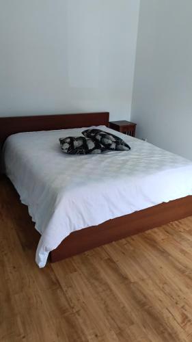 Schlafzimmer mit einem Bett mit weißer Bettwäsche und Holzböden in der Unterkunft Spacious Garden Bungalow Escape in Subang Jaya
