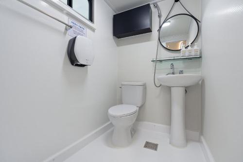 een witte badkamer met een toilet en een wastafel bij Pohang Uni's Sea Guryongpo in Pohang