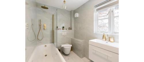 a bathroom with a tub and a toilet and a sink at Serenity in the City: Best 5BR Home in Whitechapel in London