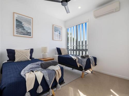 a bedroom with two beds and a chair and a window at Serenity Sands Townhouse in Kingscliff