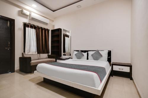 a bedroom with a large white bed and a chair at Super Townhouse1306 Hotel Prime Stay in Indore