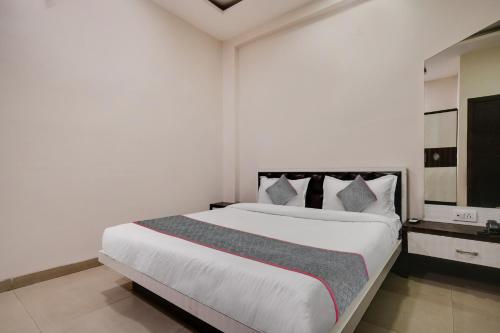 a white bedroom with a large white bed with pillows at Super Townhouse1306 Hotel Prime Stay in Indore