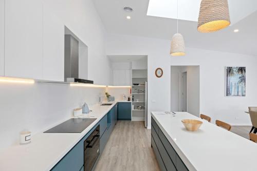 a kitchen with white counter tops and blue cabinets at Escape by the Bay in Coronet Bay