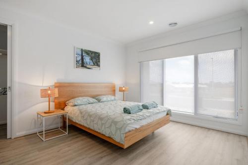 a bedroom with a bed and a large window at Escape by the Bay in Coronet Bay
