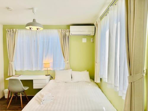 a bedroom with a bed and a desk and a window at Megu Fuji Plus in Fujiyoshida